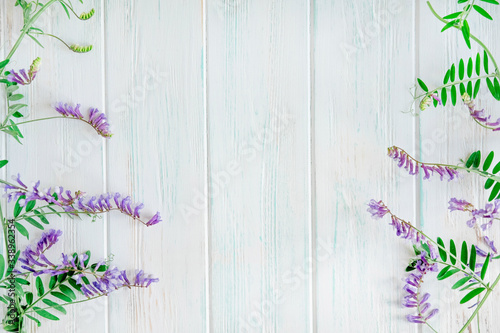 Background with curly lilac flowers on both sides of a wooden banner view from the top. Wild flowers text frame
