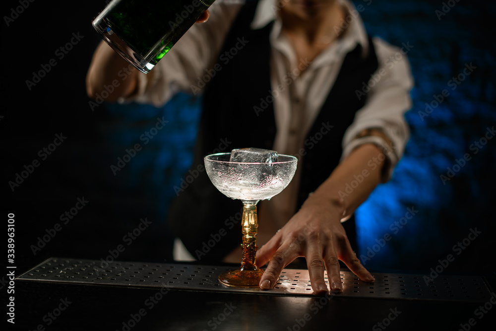 Close-up bartender begin to pour drink into glass