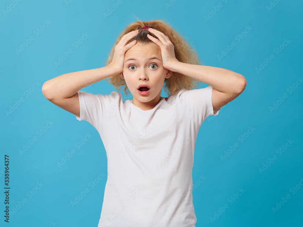 Girl holding on to her head curly hair emotions blue background Girl holding on to her head curly hair emotions blue background