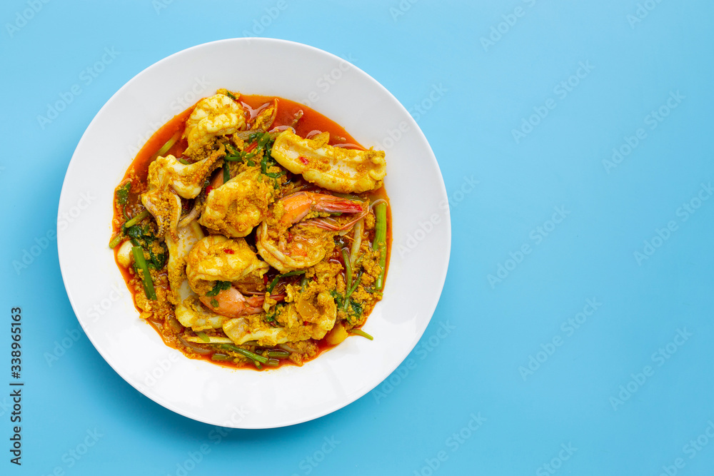 Fried seafood with curry powder on blue background.