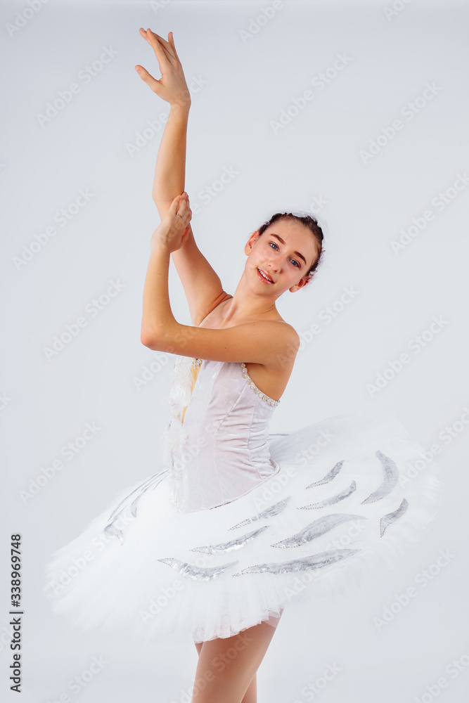 Fototapeta premium Attractive young ballerina with a beautiful body in leotard dancing tiptoes in photostudio isolated on white background. Showing the beauty of such classical art as ballet.