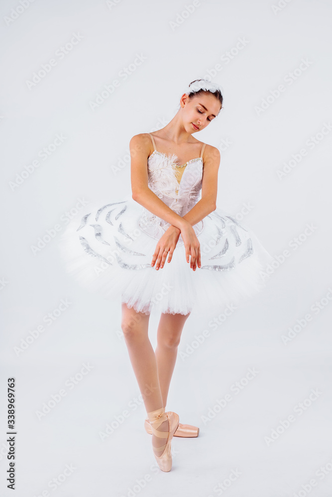Naklejka premium Glory, dream, choreography concept. Slender figure of female ballet dancer in the studio lights wearing beautiful tutu from swan lake ballet performance. Turning around like statuette in music box