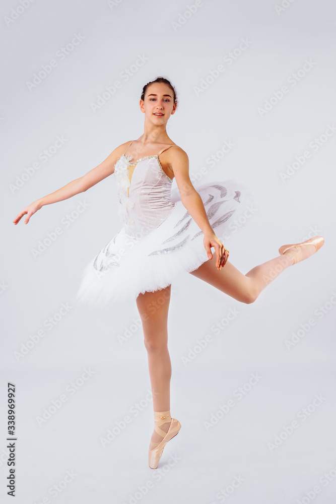 Attractive young ballerina with a beautiful body in leotard dancing tiptoes in photostudio isolated on white background. Showing the beauty of such classical art as ballet.