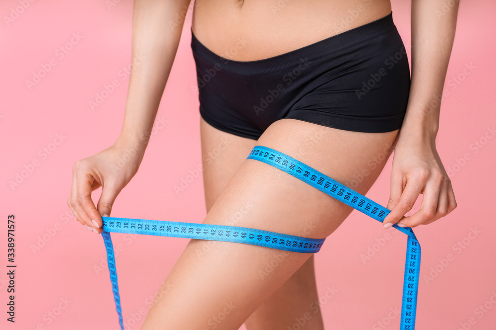 Young woman with measuring tape on color background, closeup. Weight loss concept