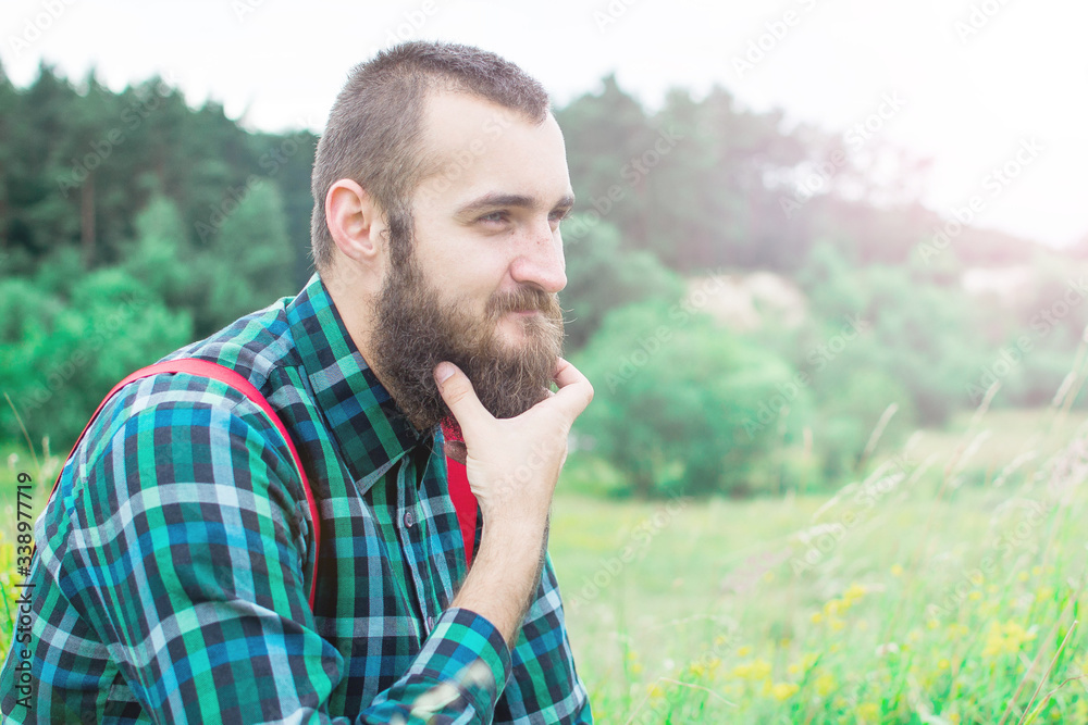 Handsome man hipster with beard on serious face in cloth shirt and suspenders sunny outdoor on mountain top against cloudy sky on natural. Tourism concept. Wonderful landscape. Handsome man hipster with beard on serious face in cloth shirt and suspenders sunny outdoor on mountain top against cloudy sky on natural. Tourism concept. Wonderful landscape.