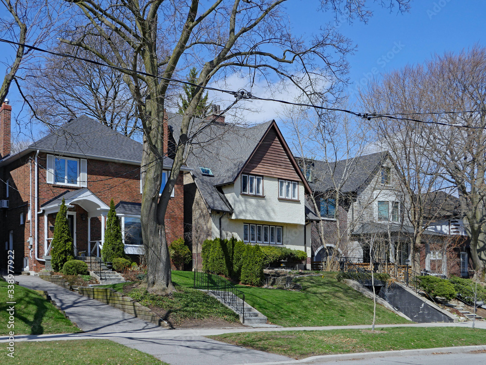 Residential street with large detached houses with front yards and mature trees