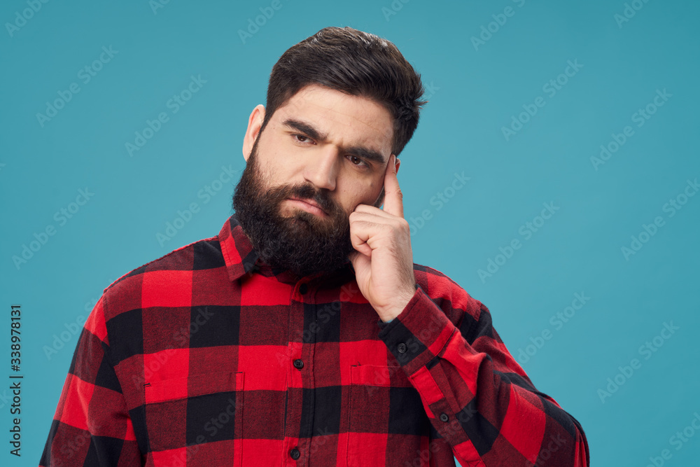 Fototapeta premium Bearded man plaid shirt pensive look studio blue background