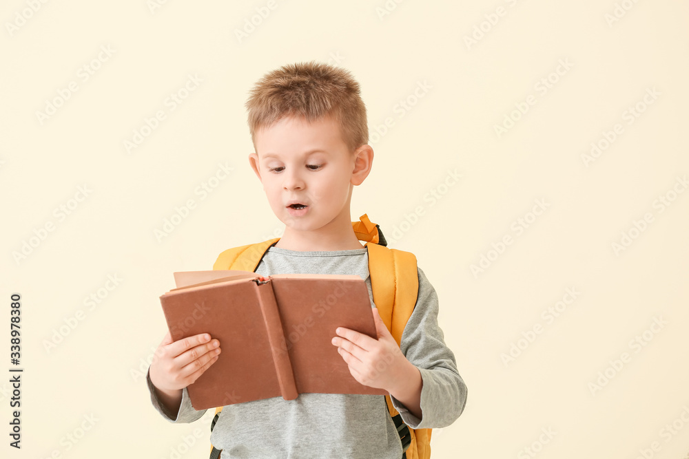 Surprised little boy reading book on color background Surprised little boy reading book on color background