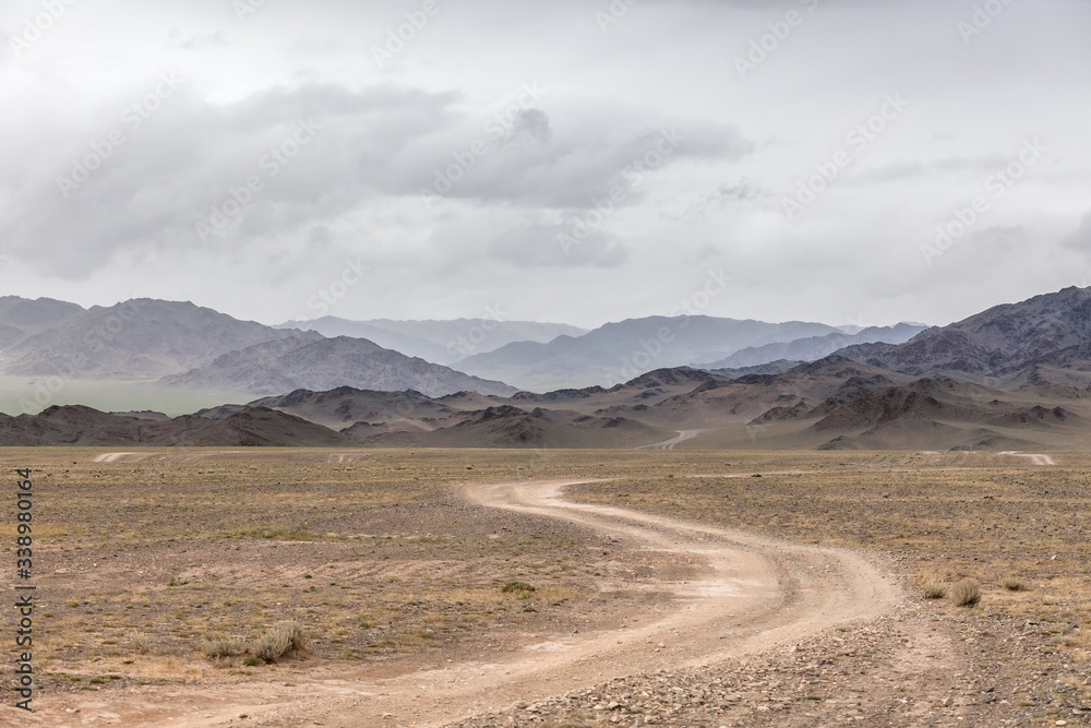 Winding dirt road through lush rolling hills of Central Mongolian steppe. Mongolian Altai