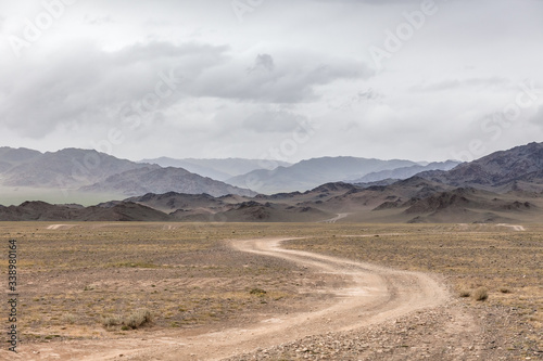 Winding dirt road through lush rolling hills of Central Mongolian steppe. Mongolian Altai