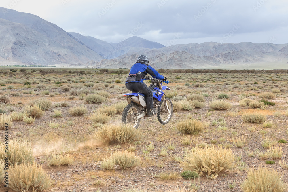 Man riding a motorbike in the steppes of Mongolia, on the hills of Mongolia Man riding a motorbike in the steppes of Mongolia, on the hills of Mongolia