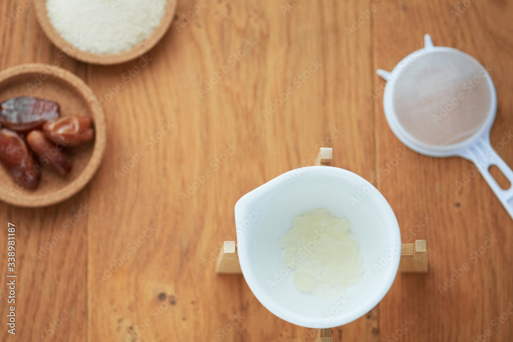 A flatlay overhead shot of the material and ingredients for water kefir drink, including dried dates and organic raw cane sugar. A flatlay overhead shot of the material and ingredients for water kefir drink, including dried dates and organic raw cane sugar.