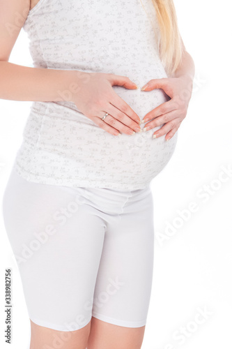 Closeup Pregnant Caucasian Woman Belly. Posing In White ShirtShirt And Pants Against Pure White Background.