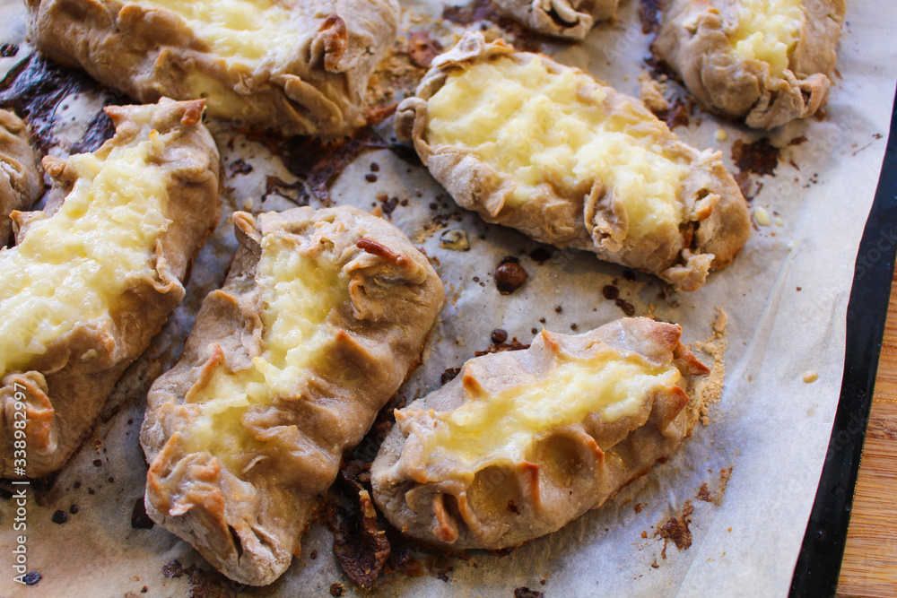 Cooked Karelian pies - Pirakka on a baking sheet. Dish of national cuisine - piirakka. Close-up. Cooked Karelian pies - Pirakka on a baking sheet. Dish of national cuisine - piirakka. Close-up.