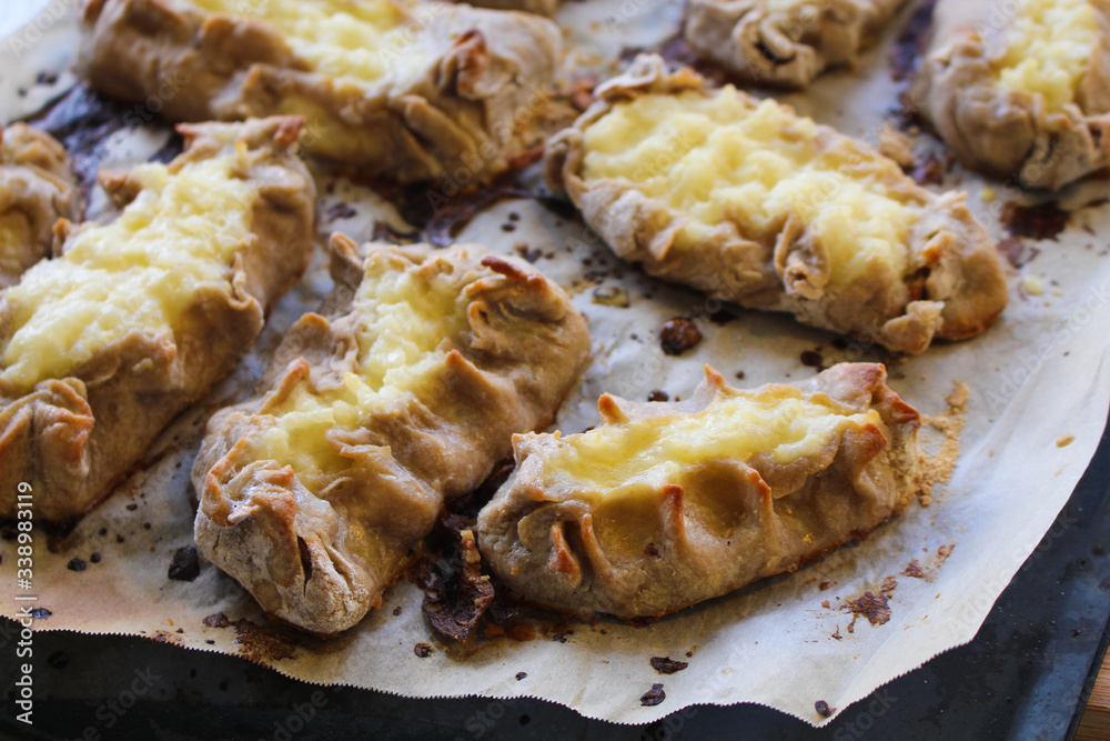 Cooked Karelian pies - Pirakka on a baking sheet. Dish of national cuisine - piirakka. Close-up. Cooked Karelian pies - Pirakka on a baking sheet. Dish of national cuisine - piirakka. Close-up.