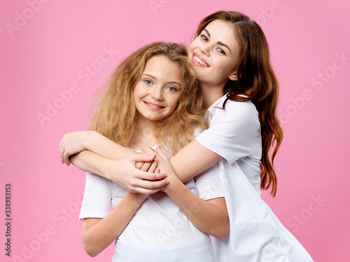 Mom and daughter hugs joy smile family pink background communication