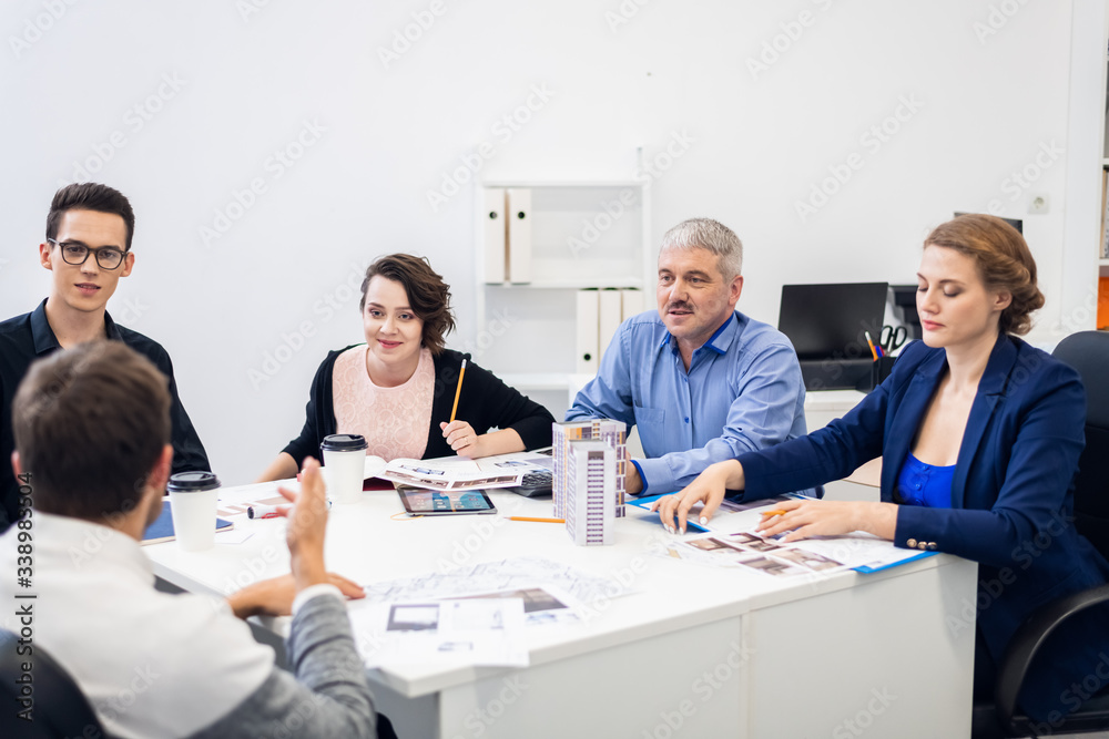 A group of architect bureau employees brainstorming together, working with the charts, studying documentation, technical drawings, models A group of architect bureau employees brainstorming together, working with the charts, studying documentation, technical drawings, models
