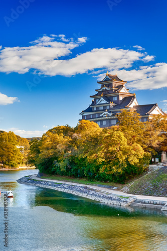 Okayama Crow Castle or Ujo Castle in Okayama City on the Asahi River in Japan. With Little Boat In Foreground. photo