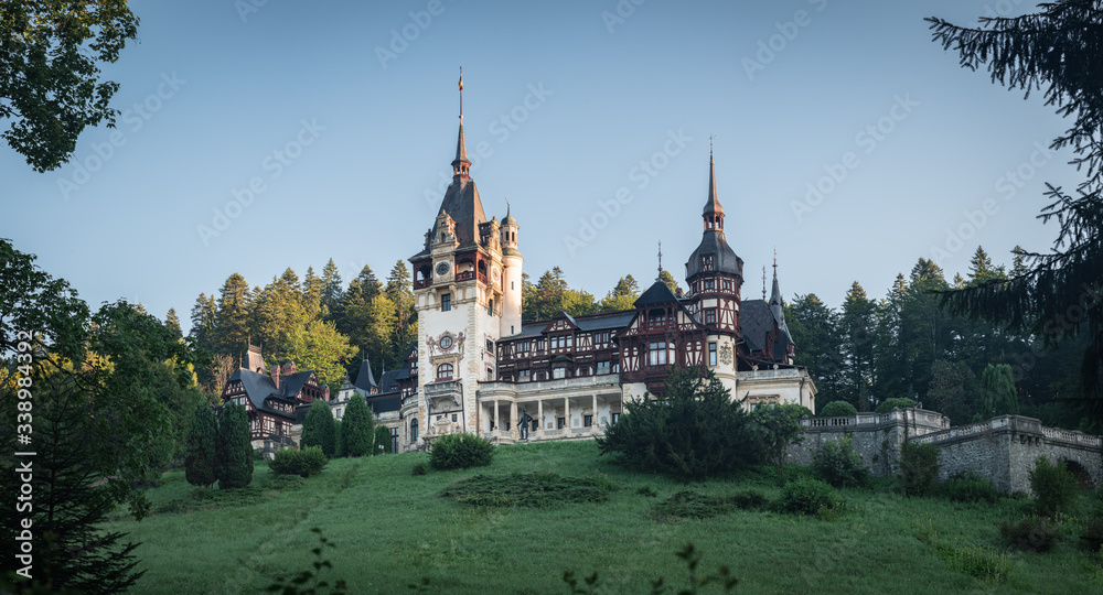 Peles Castle, famous residence of King Charles I in Sinaia, Romania. Summer landscape at sunrise of royal palace and park.
