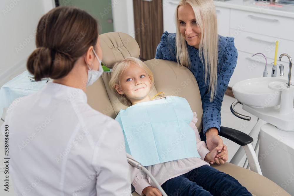 A female pediatric dental specialist going over the results of the girl's oral checkup with her mom. Dentist office A female pediatric dental specialist going over the results of the girl's oral checkup with her mom. Dentist office