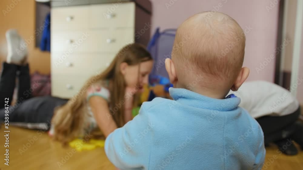 Children playing with nine month old baby, sitting on the floor at home and drawing. Children playing with nine month old baby, sitting on the floor at home and drawing.