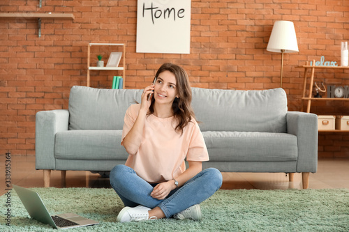 Beautiful young girl talking by phone at home