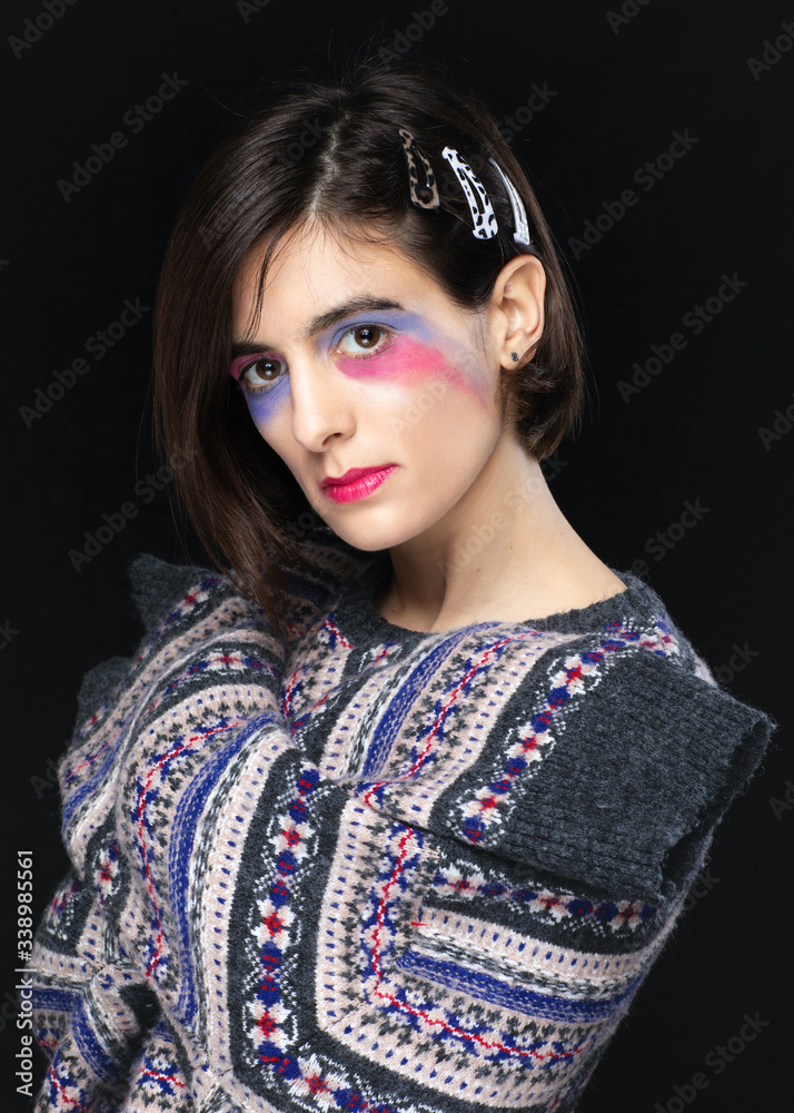 Female with creative make up and colourful sweater posing in studio. Fashion model in studio shoot. Female with creative make up and colourful sweater posing in studio. Fashion model in studio shoot.