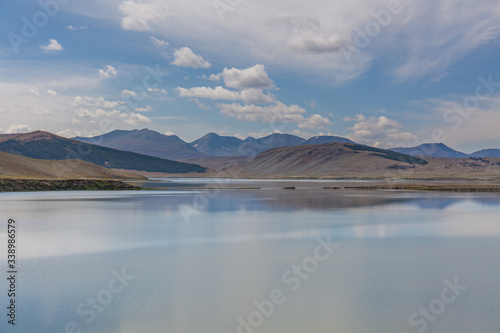 Amazing Altai natural landscape  calm lake with emerald water  surrounded by incredible mountain ice peaks with a gloomy  cloudy sky.