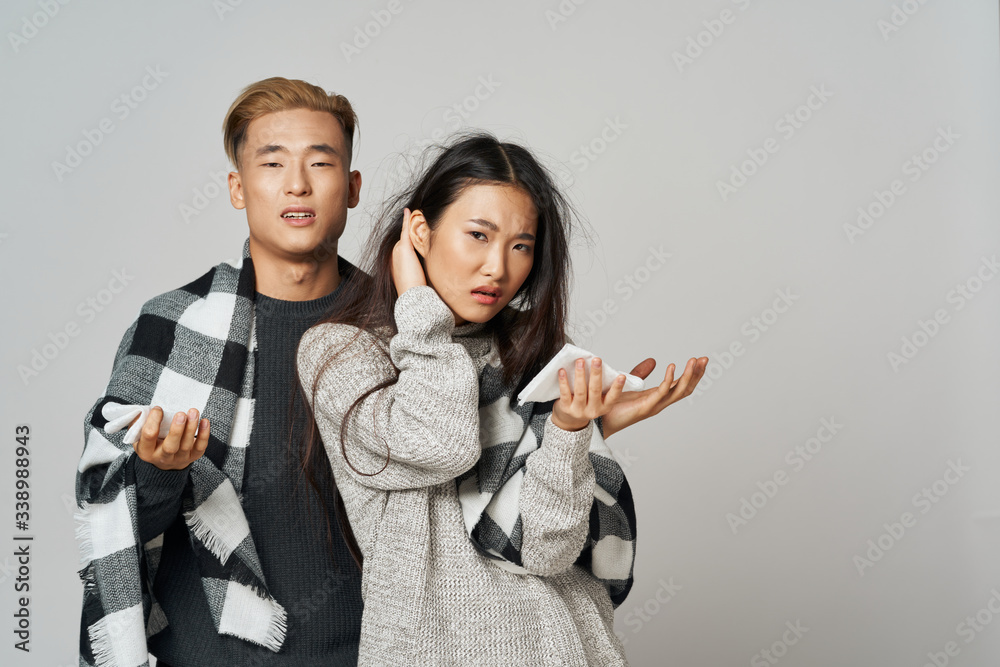 A cheerful young couple of Asian appearance hiding behind a blanket of coolness, a cold of discontent A cheerful young couple of Asian appearance hiding behind a blanket of coolness, a cold of discontent