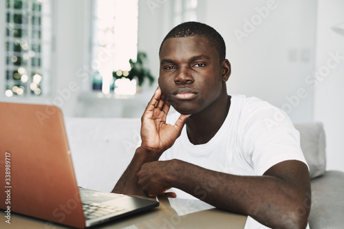 A man of African appearance at home at a table in front of a laptop