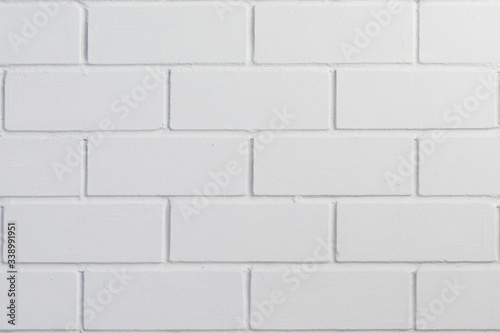 The new brick wall is covered in white paint. Background for design on the theme of construction or architecture.