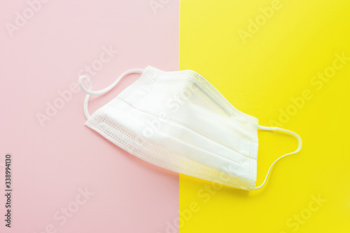 White medical mask. Yellow and pink background. Face mask protection against pollution, virus, flu, coronavirus. Health care  concept. Selective foocus. photo