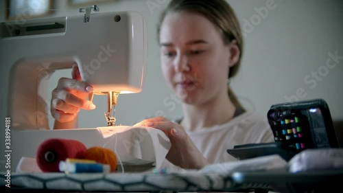 Young woman designer sewing decorative mask using a sewing machine photo