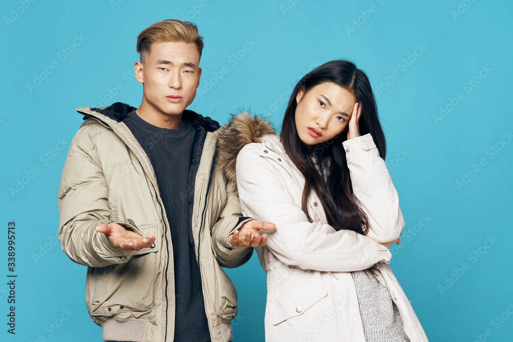 A cheerful young couple of Asian appearance in winter jackets is a fashion lifestyle
