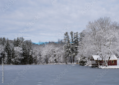 Winter landscape with a red cabin by the lake