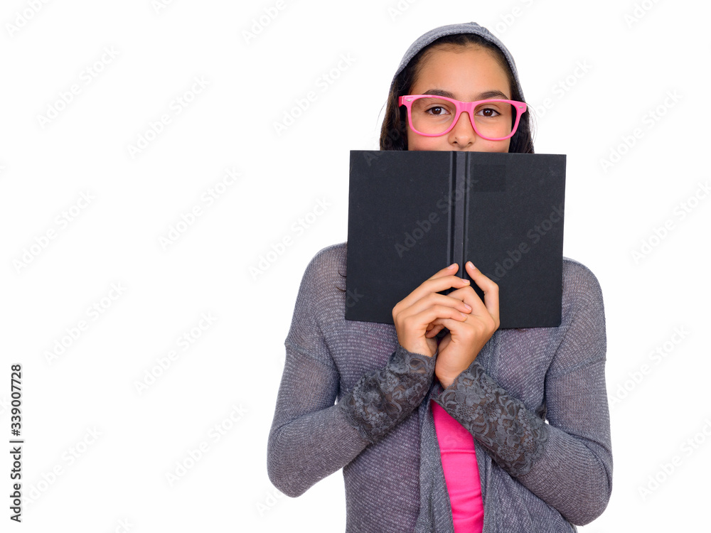 Studio shot of young beautiful teenage girl hiding behind book isolated against white background Studio shot of young beautiful teenage girl hiding behind book isolated against white background