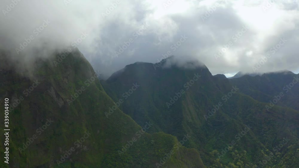 Aerial, tracking, drone shot of clouds above mountains, a valley and jungle, dark, rainy day, in Maui, Hawaii, USA Aerial, tracking, drone shot of clouds above mountains, a valley and jungle, dark, rainy day, in Maui, Hawaii, USA