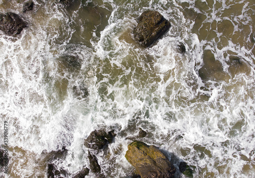 Waves in the ocean or sea breaking on stones, top view