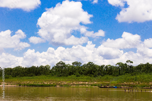 Foto del paisaje en el río Ucayali de Perú con embarcación con arboles y nubes