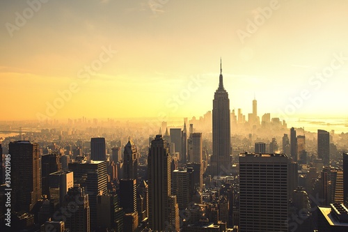 Платно Empire State Building Amidst City Against Sky At Sunset