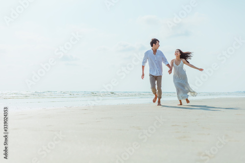 Romantic couple holding hands running and walking on beach. Man and woman in love.