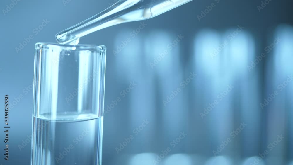 Close up of pipette with liquid inside and water drop in test tubes