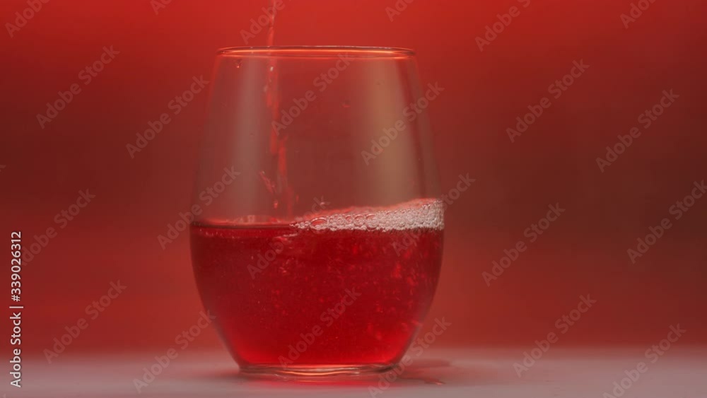 Sparkling wine pour in slow motion over red background. Sparkling wine pour in slow motion over red background.