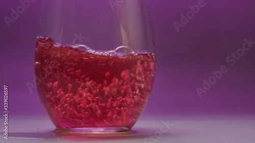 Sparkling wine pour and overflow in slow motion on purple background. photo