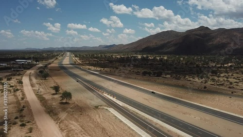 4K aerial video of newly upgraded main A1/B1 highway outside Windhoek to town Okahandja with bush covered mountains, dry endless savanna view, metal silo towers in Khomas Region, central Namibia photo