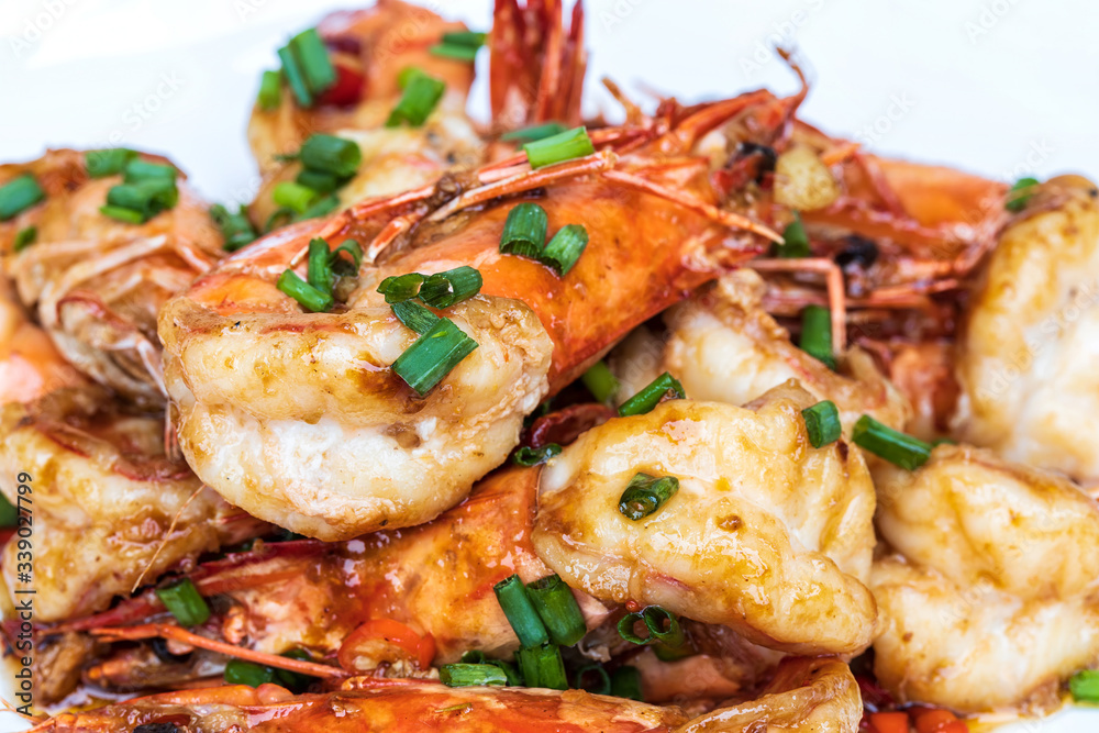 Closeup of Fried stir spicy shrimps on a white dish on wooden table. Special thai seafood. Thai Dish Cuisine. Thai food.