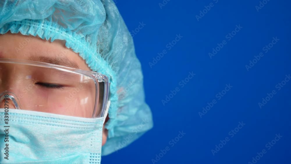 Asian boy in protective medical mask, glasses and hat on color background, closeup. Concept of epidemic