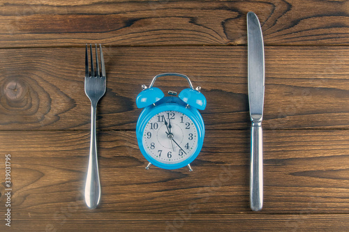 Foto One vintage clock with fork and knife on dark wood table top view