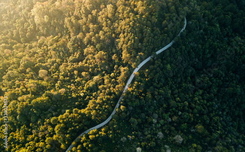 Top view of countryside road passing through the green forrest and mountain