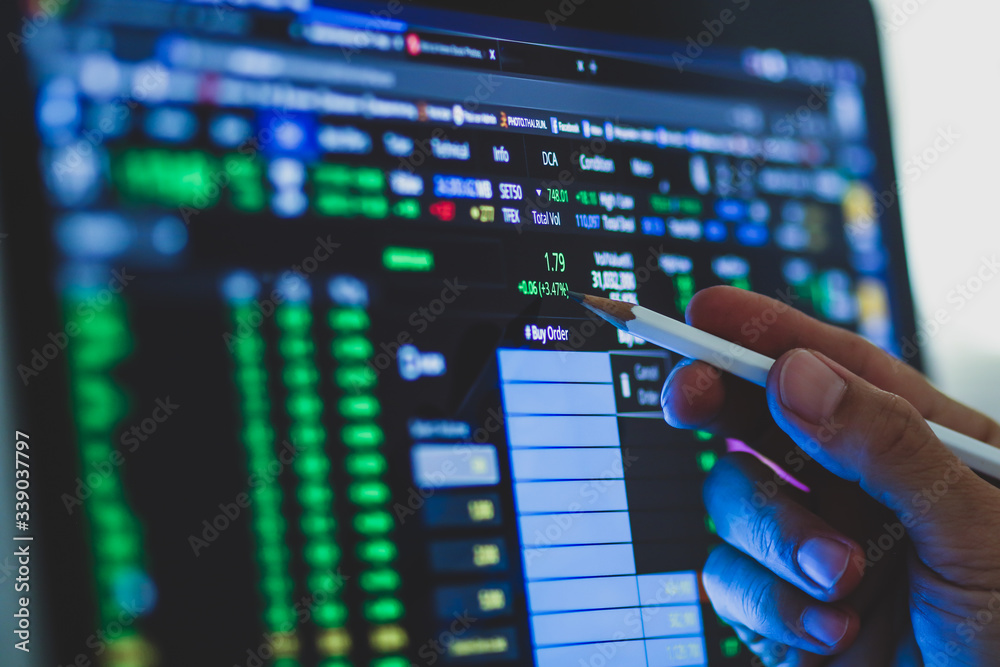 Business man hand holding pencil points to stock market graph analysis on monitor screen. Economic and financial concept. Seletive focus. Business man hand holding pencil points to stock market graph analysis on monitor screen. Economic and financial concept. Seletive focus.